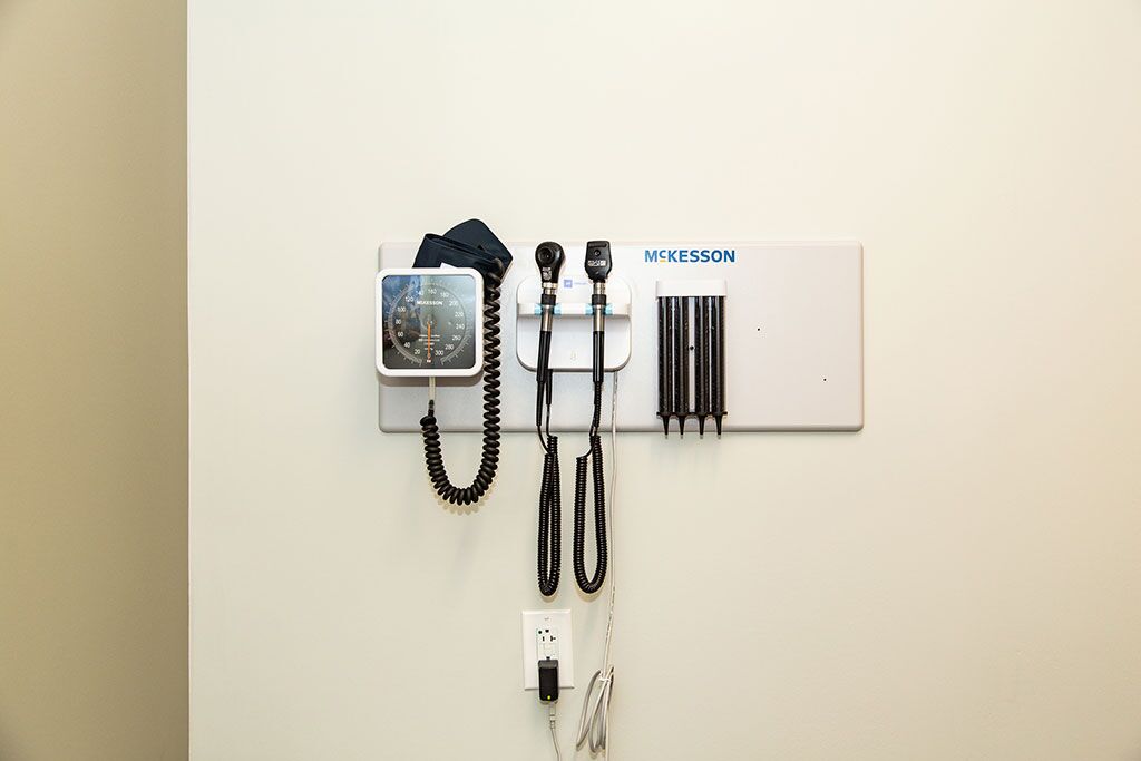 A wall-mounted medical diagnostic station with a blood pressure monitor, otoscope, ophthalmoscope, and specula dispenser. Ideal for a walk-in clinic, this station is marked with the brand "McKesson.